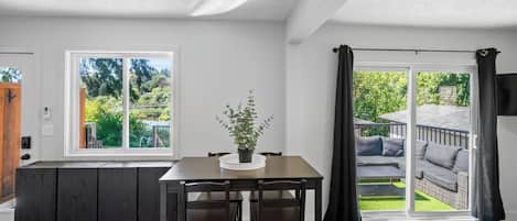 Eine moderne Küche mit Essbereich, einem großen Fenster und einer Schiebeglastür, die auf eine Terrasse im Freien führt.