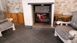 A living room with a fireplace, two patterned armchairs, and a stone wall. - La Rena Quietness and serenity at 70 km from Nice (La Penne)