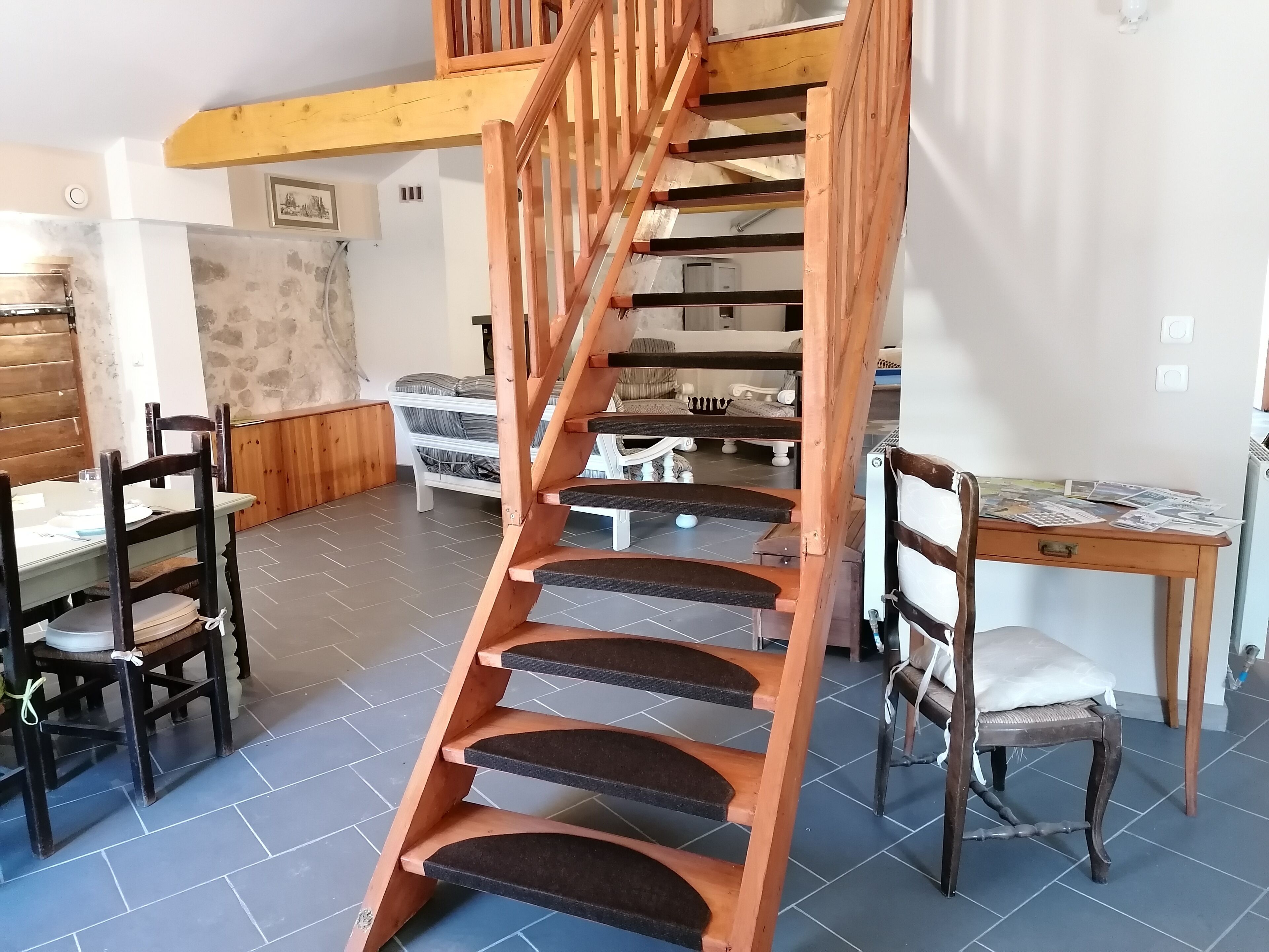 A spiral staircase with wooden steps and a wooden railing, leading to an upper floor.