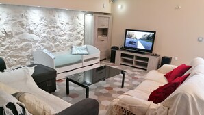 A living room with a sofa, a coffee table, a TV, and a stone wall. - La Rena Quietness and serenity at 70 km from Nice (La Penne)