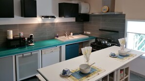 A modern kitchen with a central island, a dishwasher, a stove, and overhead lighting. - La Rena Quietness and serenity at 70 km from Nice (La Penne)