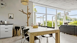 Eine moderne Küche mit Essbereich, großen Fenstern und Blick ins Grüne.