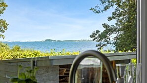 Blick aus einem Fenster auf ein Gewässer mit einem entfernten Landteil.