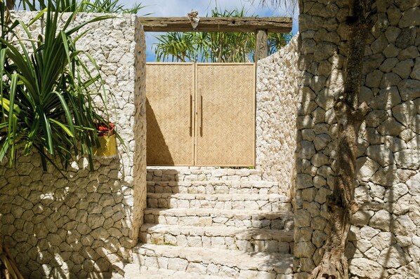 A stone staircase leading to a wooden door with a herringbone pattern. - The Cabins (Lembongan Island)