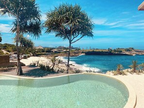 A pool with clear water, surrounded by palm trees and a view of the ocean. - The Cabins (Lembongan Island)