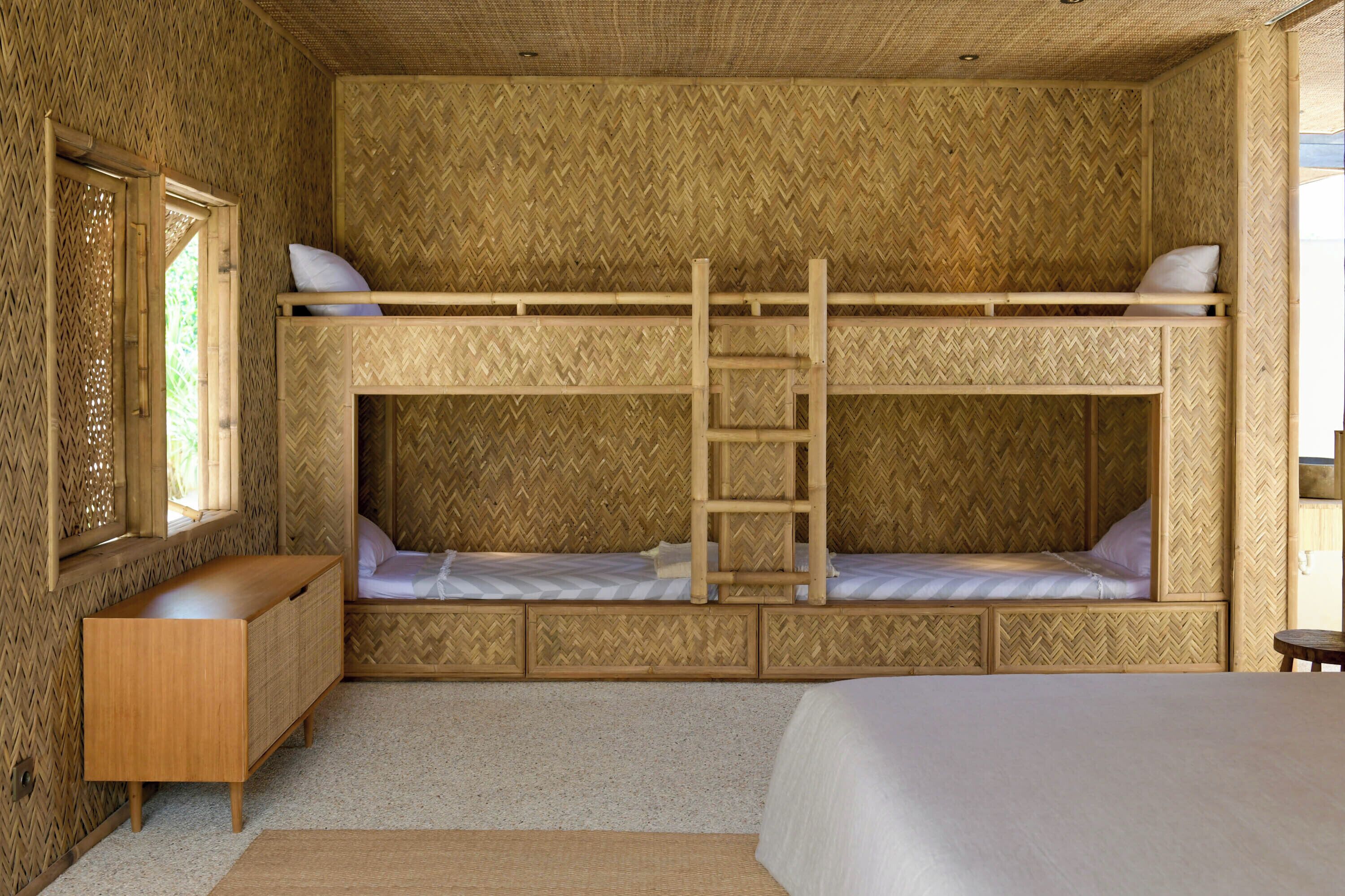 A bunk bed room with a ladder, a wooden dresser, and a window.