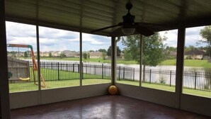 Un patio couvert doté d’un sol en béton, de grandes fenêtres et d’un ventilateur de plafond.