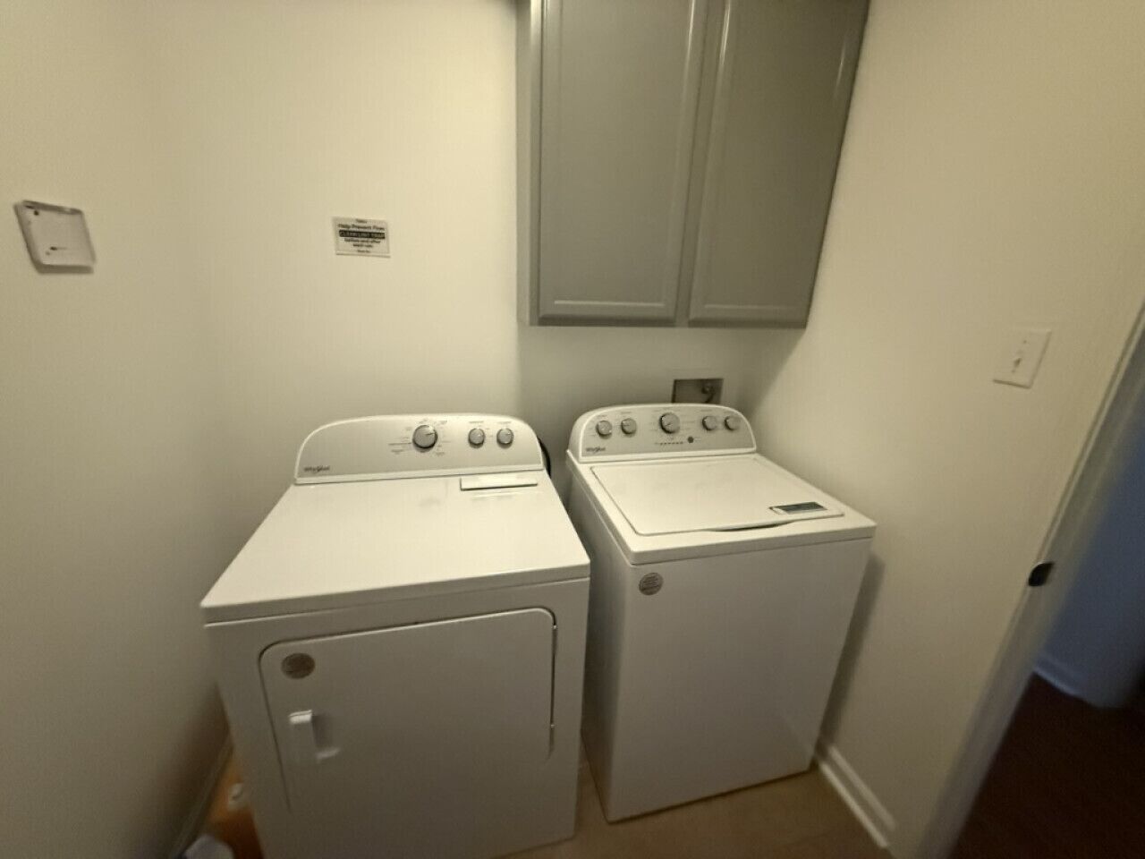 Une buanderie équipée de deux machines à laver à chargement frontal, toutes deux blanches, et d’un petit miroir placé au-dessus.