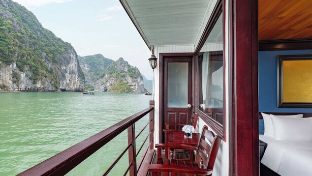 A balcony with a wooden railing overlooking a body of water and a mountainous landscape. - Garden Bay Legend 2 cruise (Bai Chay)