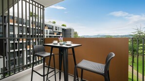 A balcony with two chairs and a table, a view of a modern building, and a clear sky. - Laguna Skypark B2512 (Choeng Thale)