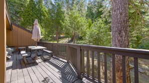 A wooden deck with outdoor seating and a view of a forest.