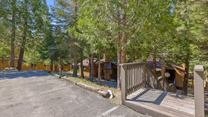 A row of cabins with a wooden deck and a gravel driveway.