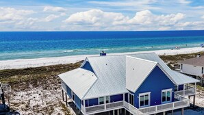 Une maison située en bord de mer, dotée d’un balcon, d’une véranda et offrant une vue sur l’océan.