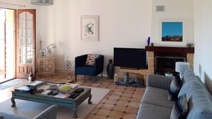 A living room with a sofa, a coffee table, a TV, a fireplace, and a door with glass panels. - 3 bedroom cozy home in Villamblard (Villamblard)