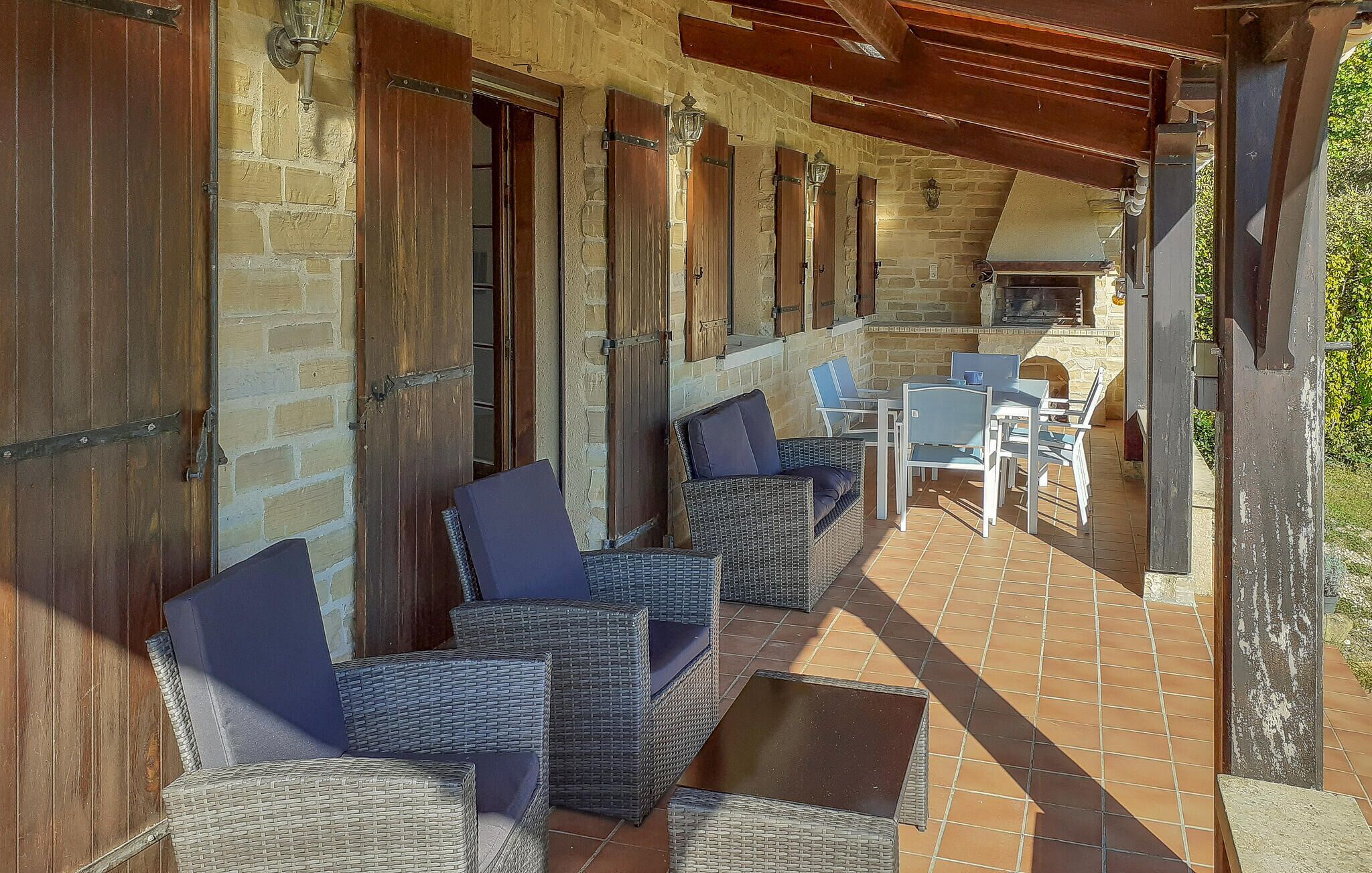 Une terrasse extérieure avec des meubles en osier, des murs en pierre et un sol en briques.