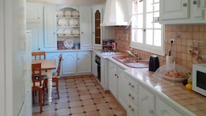 A kitchen with white cabinets, a tiled floor, a stove, a sink, and a dining area with a table and chairs. - 3 bedroom cozy home in Villamblard (Villamblard)