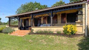 A two-story stone building with a covered patio and a small garden area with yellow flowers. - 3 bedroom cozy home in Villamblard (Villamblard)
