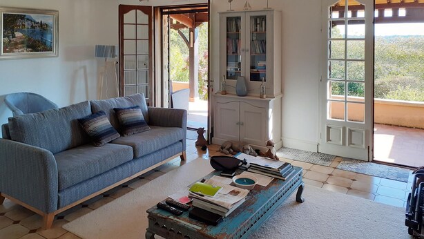 A living room with a blue sofa, a coffee table with books and a remote, and a view through the open door. - 3 bedroom cozy home in Villamblard (Villamblard)