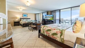 A hotel room with a bed, a desk, a chair, a TV, and a balcony with a view. - Perch - Oceanfront Tranquility: 1BR Condo w/ Views (Lahaina)