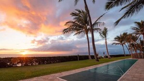 A scenic view of a pool area with palm trees and a sunset. - Perch - Oceanfront Tranquility: 1BR Condo w/ Views (Lahaina)