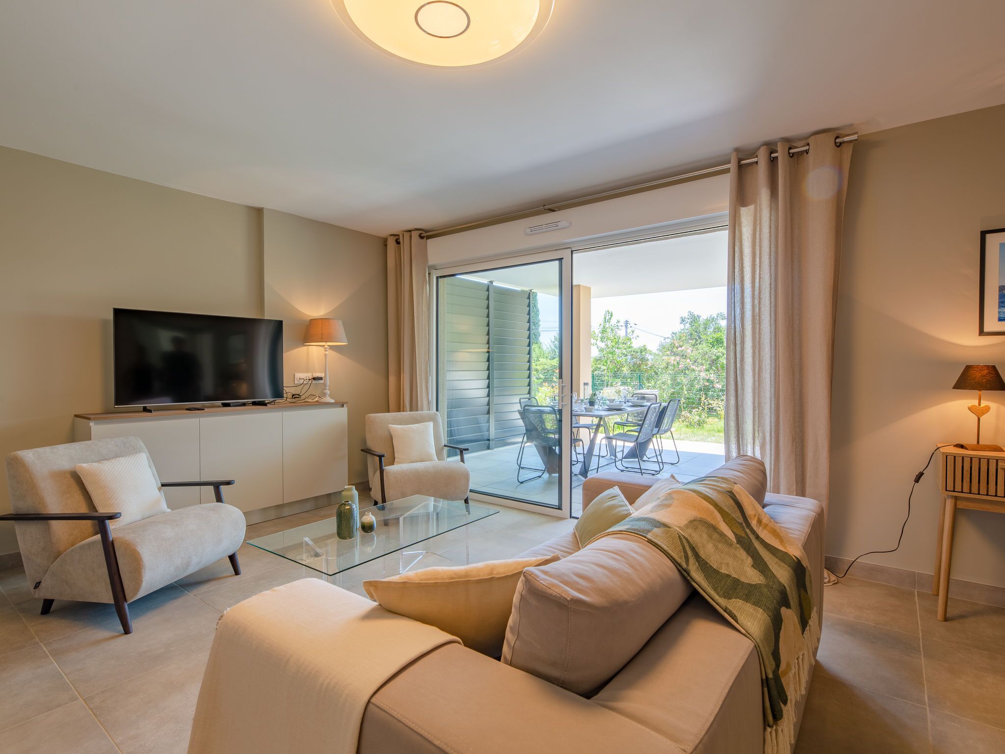 Ein modernes Wohnzimmer mit Flachbildfernseher, Glastisch und Sofa.