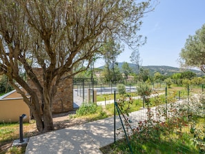 Stroll through the serene landscape, surrounded by rolling hills and a tranquil atmosphere, with a paved pathway leading to a charming building.