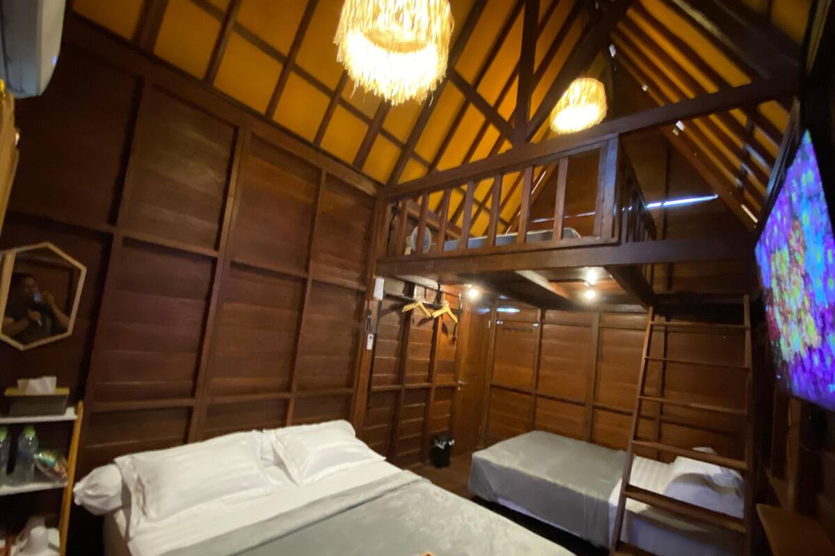 A wooden room with bunk beds, a small table, and a television.
