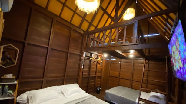 A wooden room with bunk beds, a small table, and a television.