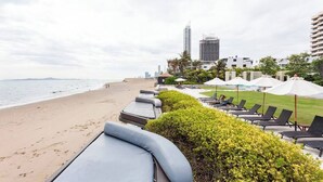 A beachside hotel with lounge chairs and umbrellas, a pool, and a view of the city skyline. - Family Suite Sea view 2Bedroom  (Pattaya)