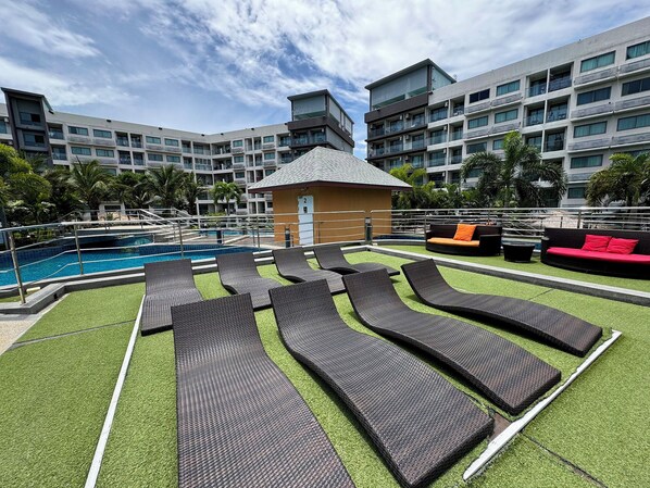 A rooftop pool area with lounge chairs, a small pool, and a building in the background.