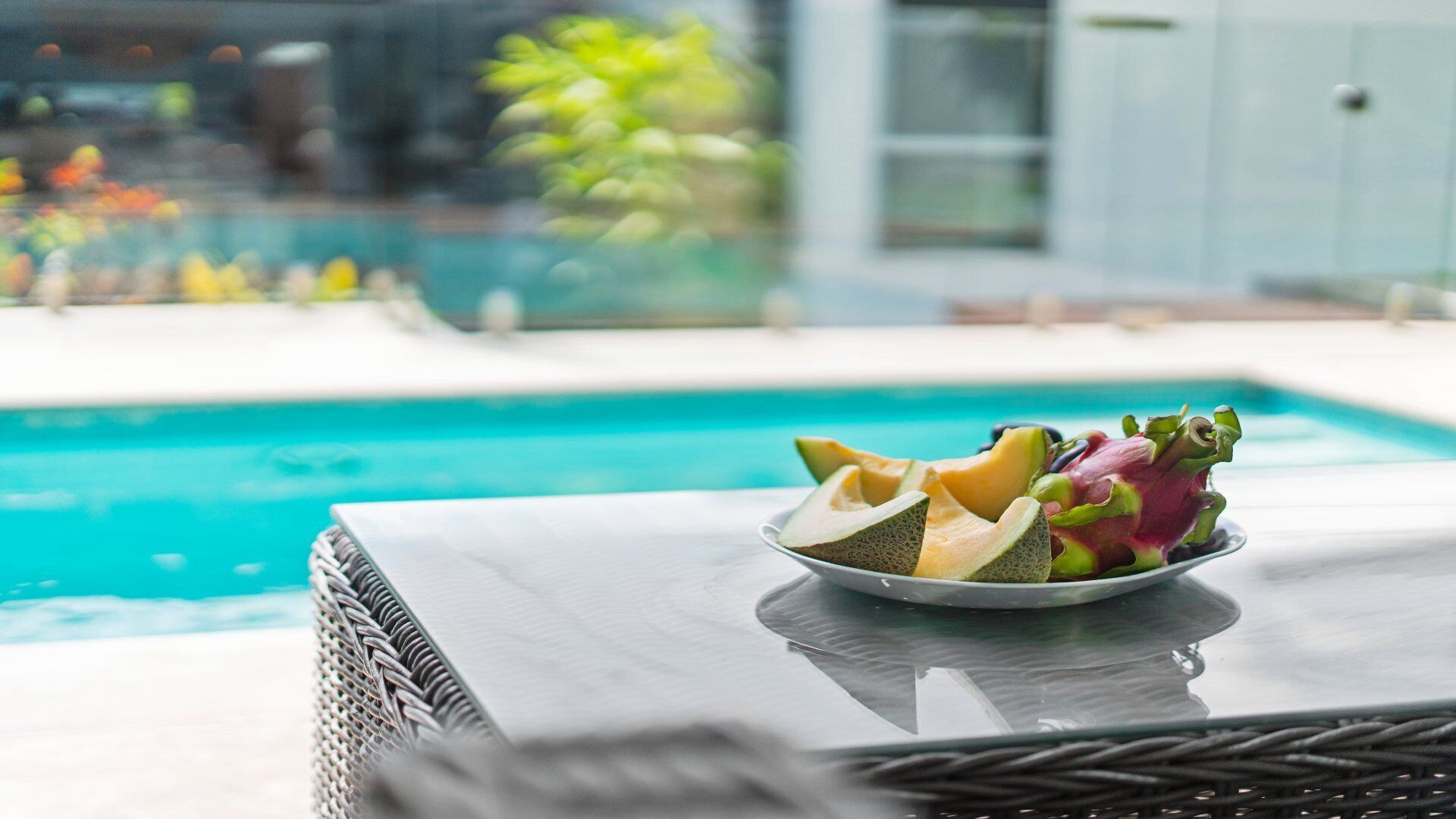 Ein Esstisch mit Obstschale und Blick auf einen Swimmingpool.