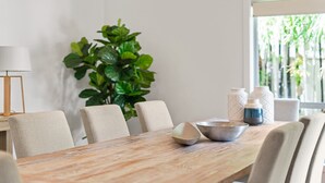 Een eetgedeelte met een houten tafel, stoelen en een potplant.