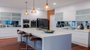Een moderne keuken met witte kastjes, roestvrijstalen apparatuur en een centraal eiland met barstoelen.