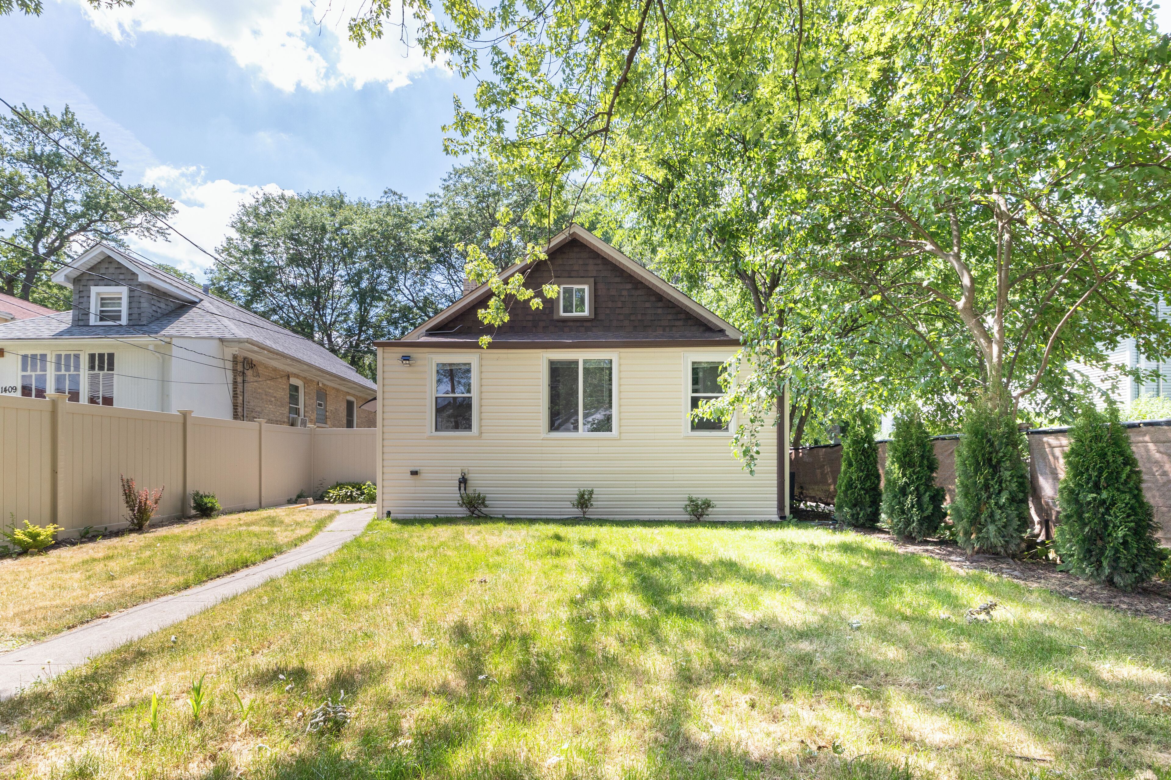 A single-story house with a front yard, a pathway leading to the entrance, and a small tree in the front yard.