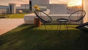 A rooftop terrace with modern chairs, a small table, and a potted plant. - Jardines Guadaiza 2 | Sea Views Terrace Bbq (Marbella)