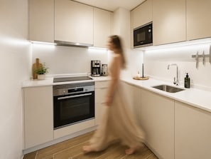 Une cuisine moderne avec des meubles blancs, un four Bosch, une machine à café et un four à micro-ondes.