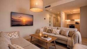 A living room with a sofa, a coffee table, a hanging lamp, and a kitchen in the background. - Jardines Guadaiza 2 | Sea Views Terrace Bbq (Marbella)
