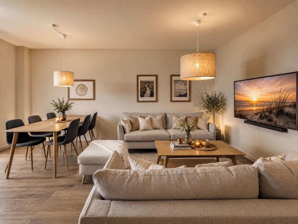 A modern living room with a dining area, a sofa, a coffee table, and a TV mounted on the wall.