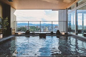 A modern indoor pool with a city view, large windows, and a wooden ceiling. - Dogo Hotel Kowakuen Haruka (Matsuyama)