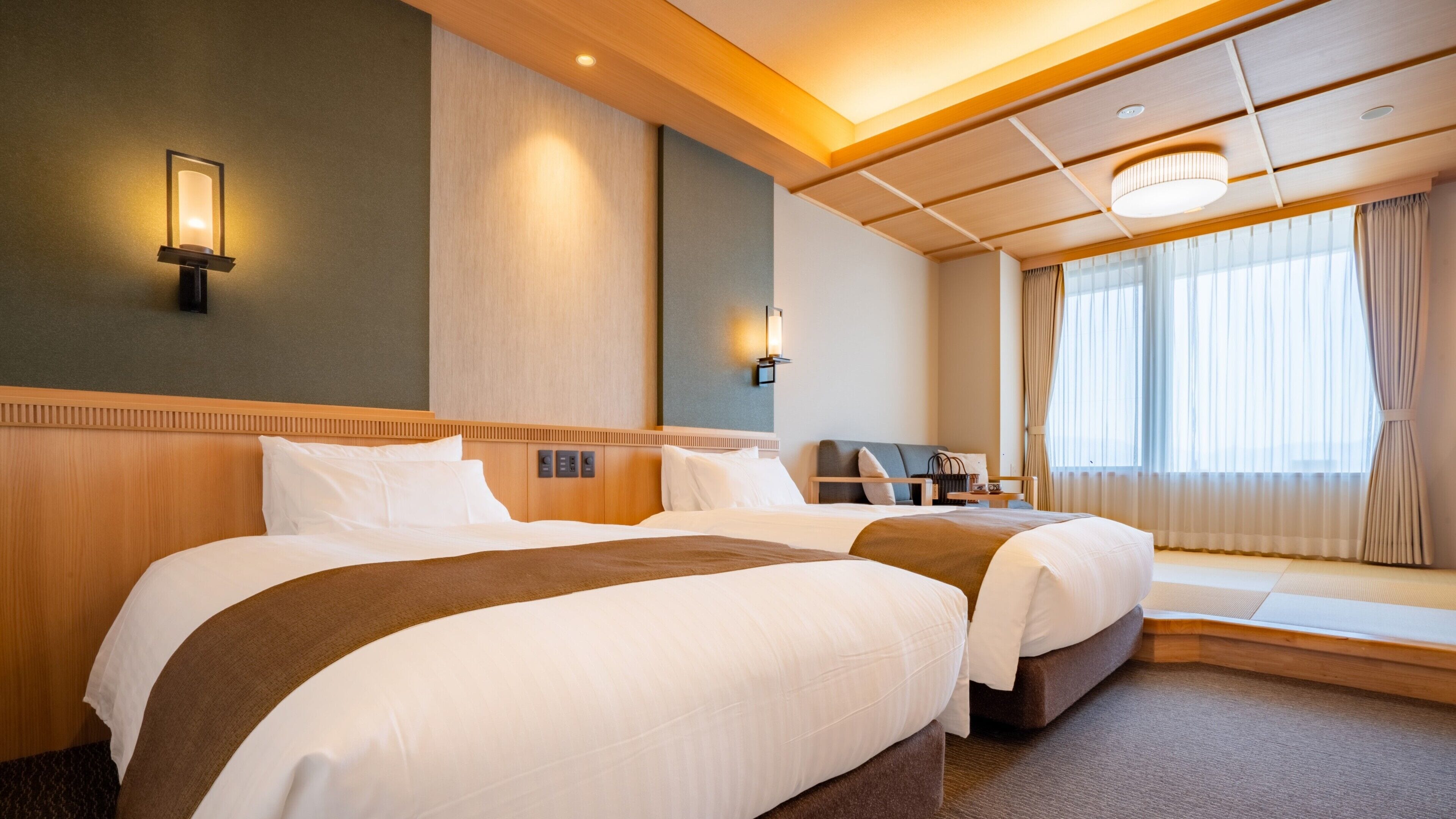A hotel room with two beds, a nightstand, a lamp, and a window with curtains.