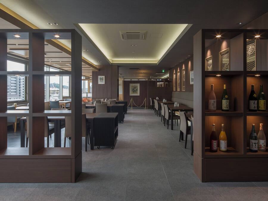 Un restaurante con una decoración moderna, que cuenta con una barra larga, cabinas y una exhibición de vinos.