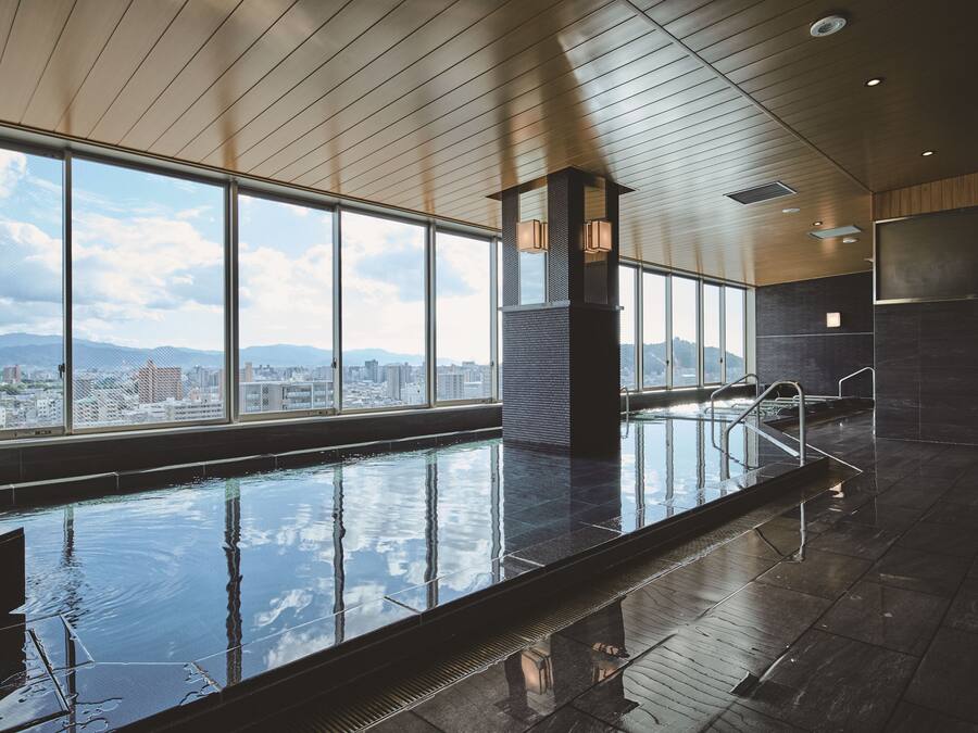 Une piscine intérieure moderne avec vue sur la ville, de grandes fenêtres et un plafond en bois.