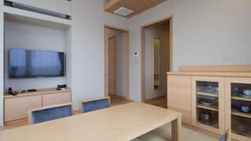 A modern living room with a flat-screen TV, wooden furniture, and a dining area with a table and chairs.