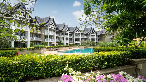 Un hôtel doté de nombreux balcons, d’une piscine et de jardins bien entretenus.