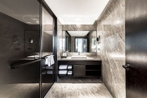 Un baño moderno con cabina de ducha de vidrio, tocador de mármol y un espejo grande.