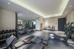 Un gimnasio con cintas de correr, mancuernas, bancos y una bicicleta estática.