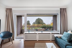 A modern living room with a large window, a sofa, a chair, and a coffee table.