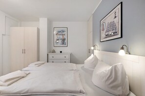 A hotel room with a bed, a nightstand, a wardrobe, and two wall-mounted lamps.