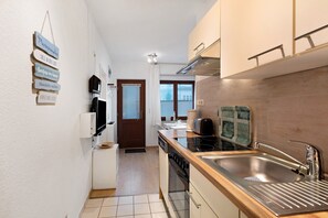 A compact kitchen with a sink, stove, and cabinets.