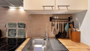 A modern kitchen with a stainless steel sink, a black stovetop, and wooden flooring. - Apartment 'Ferienwohnung Strandquartier' with Private Terrace and Wi-Fi (Lübeck Travemünde)